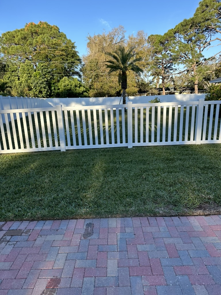 White vinyl picket fence along a paver driveway