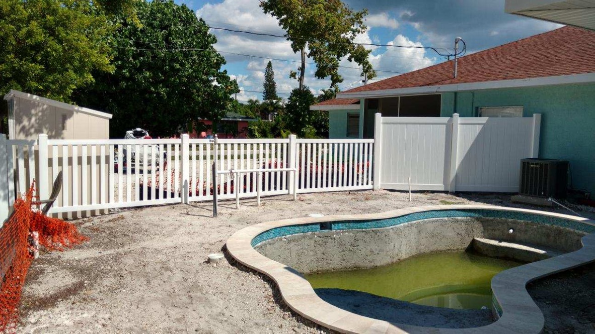 White vinyl picket and privacy fence around a pool